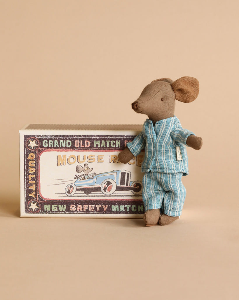 The Maileg Big Brother Family Room Set features a small mouse in blue striped pajamas beside a vintage-style "Mouse Race" matchbox, adding charm to any dollhouse collection.