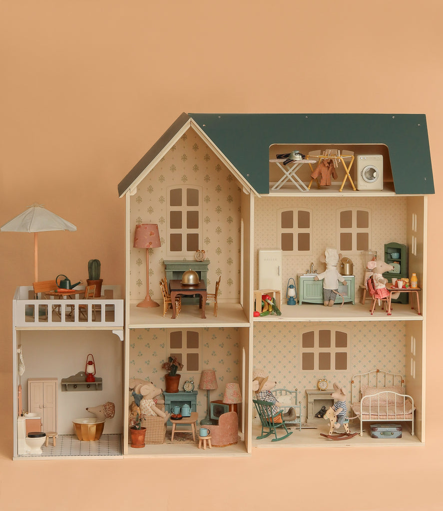 The Maileg Fully Furnished Dollhouse Set + Gift With Purchase features multiple rooms filled with miniature furniture, accessories, and animal dolls posed in daily life scenes, all set against a soft beige background.