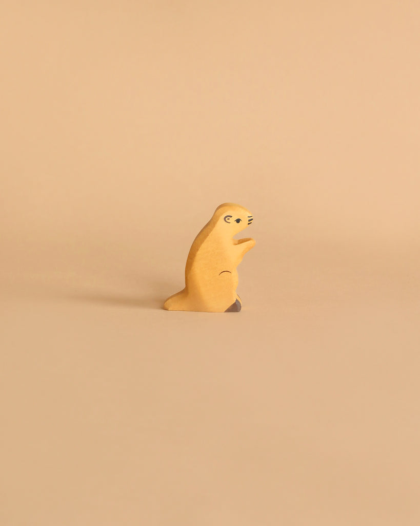 A small handcrafted wooden figure of a meerkat stands upright against a light beige background. The Holztiger Groundhog is crafted simply, with minimal details to represent the meerkat's eyes, nose, and limbs. Made in Europe, it exudes charm and simplicity.