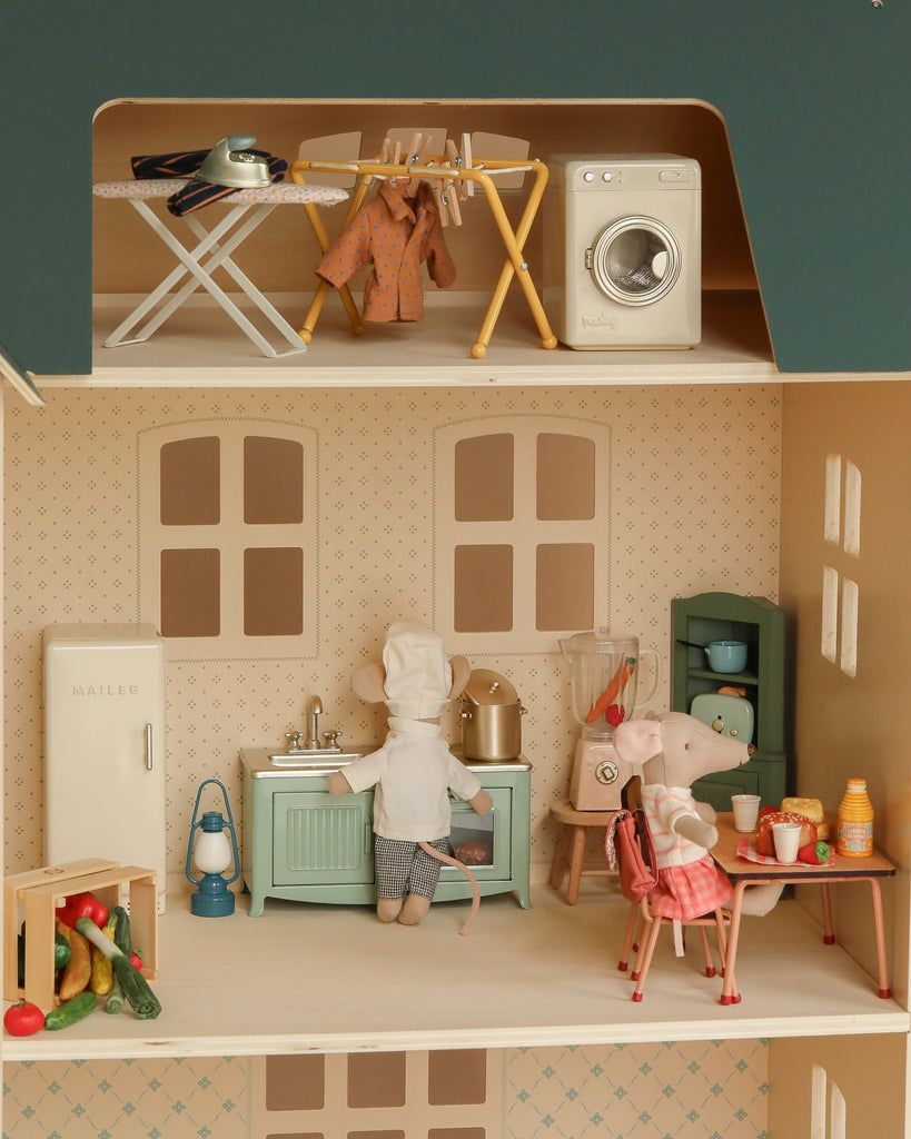 The Maileg Fully Furnished Dollhouse Set + Gift With Purchase lets kids imagine scenes like two mice cooking and enjoying breakfast, with toy laundry drying on racks near a mini washing machine and iron upstairs.