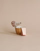 A dog-like stuffed animal with a textured hat sits in a gold bathtub from the Maileg Bathroom Set, with a pink and white striped towel draped over the side against a plain beige background.