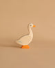A small duck from the Holztiger Handmade Wooden Woodland Animals Set, crafted from maple and beech wood, is painted white with an orange beak and feet, shown on a plain beige background.