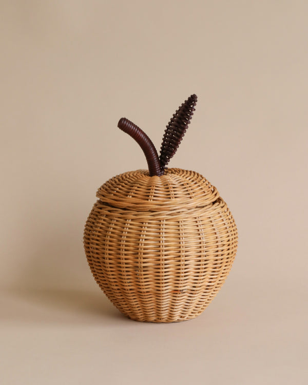 A Braided Apple Storage shaped like an apple, with a textured stem and leaf detail on top, set against a plain beige background.