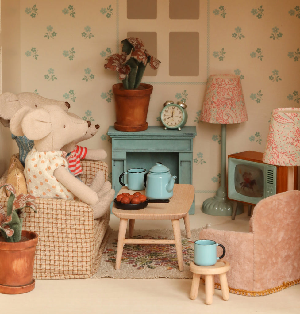 Two mice relax in the cozy Maileg Fully Furnished Dollhouse Set + Gift With Purchase, featuring tea and pastries, a blue teapot, potted plants, lamps, a clock on the mantel, and charming vintage details.