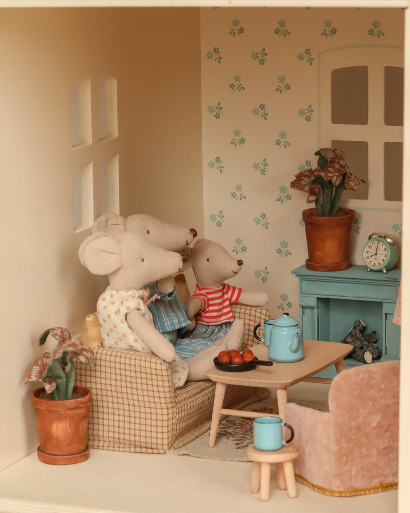 Three stuffed animal mice relax in a cozy Maileg Fully Furnished Dollhouse Set + Gift With Purchase, featuring a sofa, coffee table, blue teapot, mugs, pastries, potted plants, and vintage décor for a warm and inviting scene.