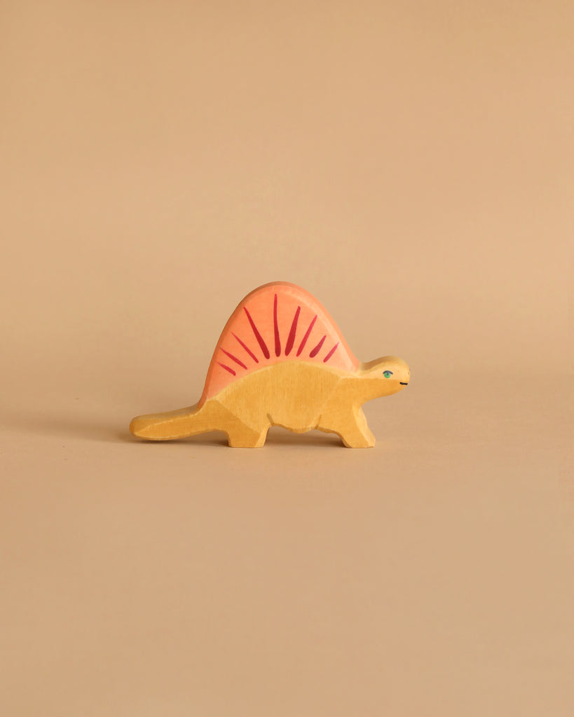 A Holztiger Dimetrodon Dinosaur with a yellow body and a pink, fin-like structure on its back stands against a light beige background. This handcrafted wood figure features a simple design, painted eyes, and minimal detailing, reminiscent of the charming HOLZTIGER figures made in Europe.