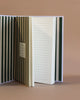 The Studious Dogs Embroidered Journal features vertical dark green and cream stripes on the cover and endpaper, lined pages inside, and is set against a beige background—a charming keepsake for your thoughts.