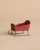 The Maileg Sleigh, Mouse - Red is a small, vintage-style wooden sleigh with metal runners, hand-painted details, and a simple decorative motif on the backrest, shown on a neutral beige background.
