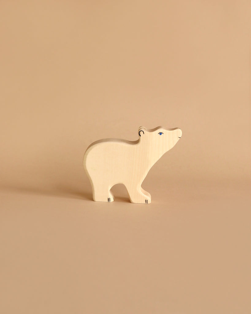 A Holztiger Polar Bear, Small, Head Raised with a light natural finish stands against a neutral beige background. Modeled in the simple, stylized form of HOLZTIGER figures, it emphasizes minimal details and showcases its natural wood grain texture.