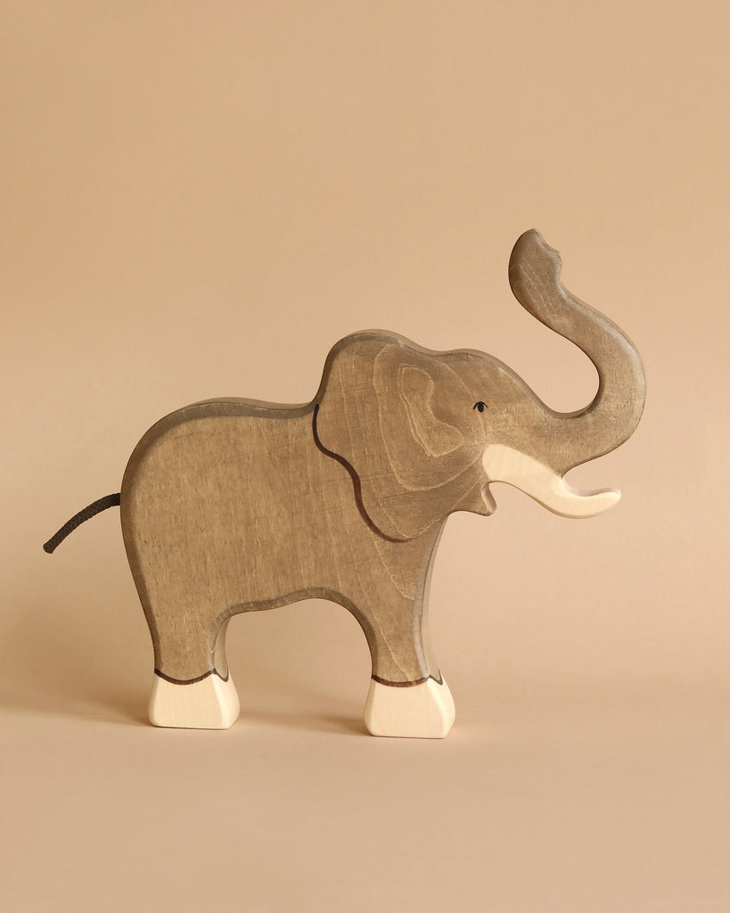 The Holztiger Handmade Wooden Safari Animals Set features a wooden elephant figurine with a raised trunk, painted in natural wood tones and white accents—ideal for fans of handcrafted figures and wooden toys.