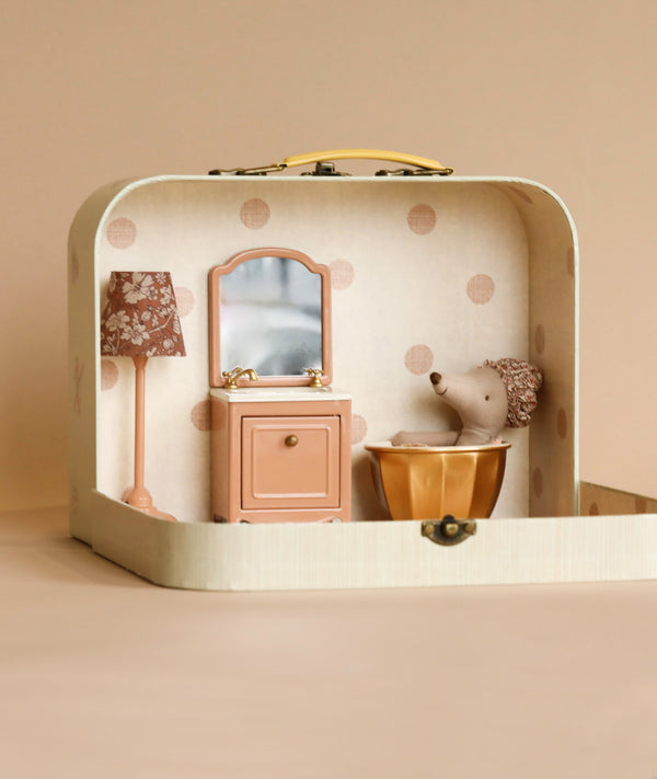 A Maileg Spa Starter Set miniature room setup inside a carry suitcase, featuring a plush elephant beside a tiny dresser with a lamp and mirror, set against a cream background with polka dots.