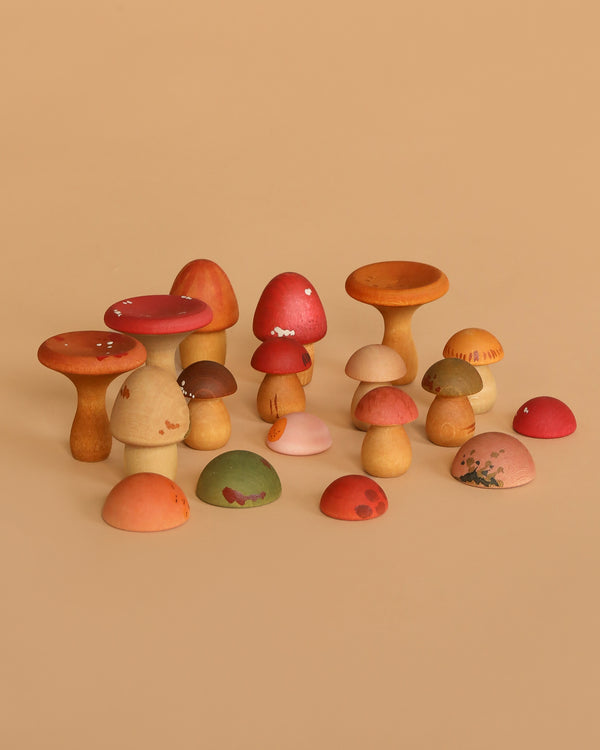 The Grapat Play Set - Mushroom Grove features hand-painted wooden mushrooms in earthy red, orange, brown, green, and pink tones. These sustainable toys inspire imaginative play with their assorted shapes and sizes.