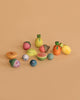 The Grapat Play Set - Fruits, featuring colorful wooden pieces like watermelon, orange, lemon, pineapple, blueberries, and acorns for open-ended play, is displayed on a plain beige background.
