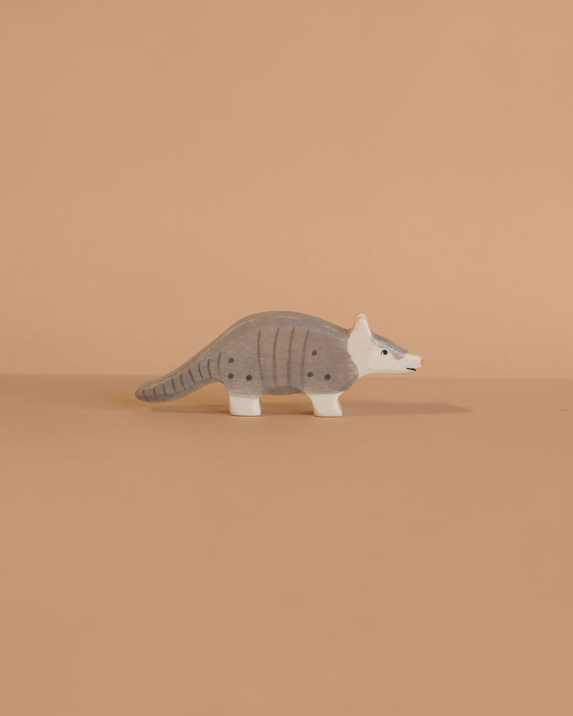 The Holztiger Armadillo is a small, gray wooden figurine with black spots and a white face, handcrafted in Europe, capturing the charm and quality of classic HOLZTIGER toys.