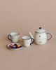 A Maileg | Miniature Tea & Biscuits for Two with a spotted design, featuring a teapot and two cups with saucers on a beige background. One saucer holds colorful candies.