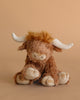 Meet Harold the Highland Cow Plush Toy by Mon Ami—a cuddly stuffed animal with soft brown fur, white horns, and a beige snout, perfect for snuggling.