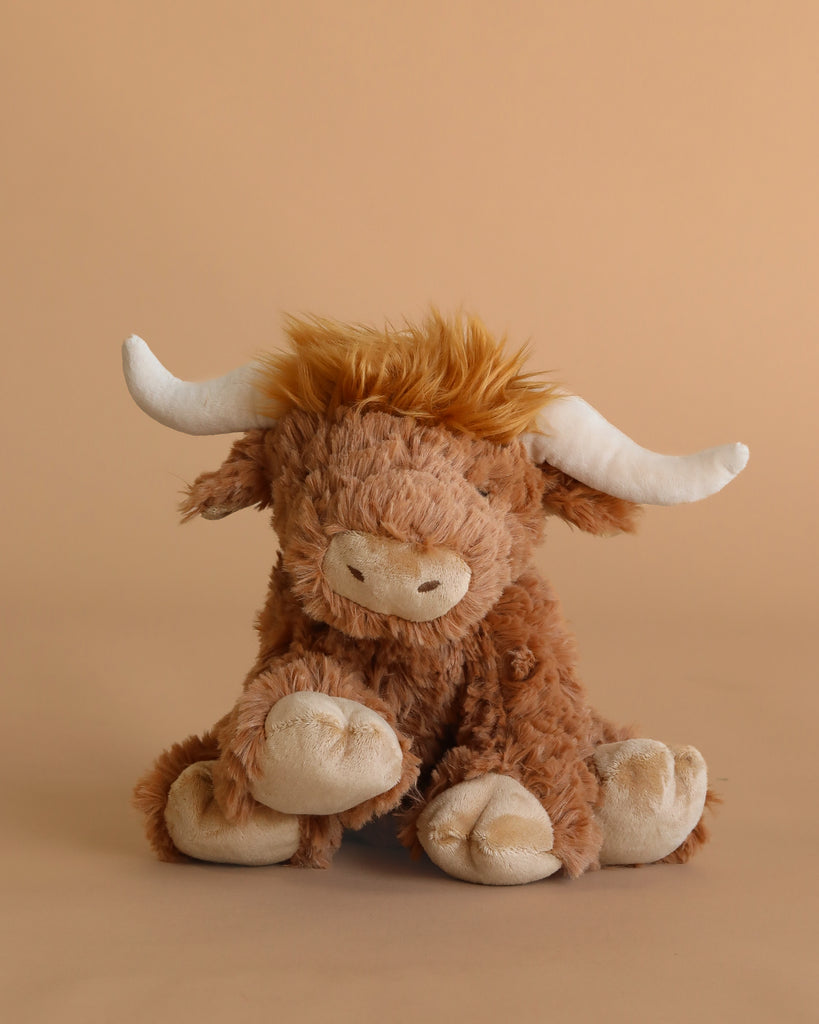 Meet Harold the Highland Cow Plush Toy by Mon Ami—a cuddly stuffed animal with soft brown fur, white horns, and a beige snout, perfect for snuggling.