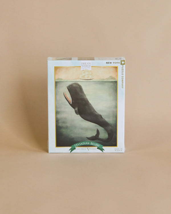 A Emily Winfield Martin, Leviathan Below Puzzle - 500 Piece of "Leviathan Below" by Dream Whaled, displayed against a plain beige background. The cover features an artwork of a whale's tail submerged in foggy water, resembling.