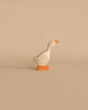 A goose from the Holztiger Handmade Wooden Woodland Animals Set, crafted from maple and beech with an orange beak, feet, and light blue wing details, stands against a plain beige background.