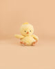 A Bukowski - Baby Chicky plush toy, small and yellow with black eyes, an orange beak and feet, sits facing forward on a light peach background.