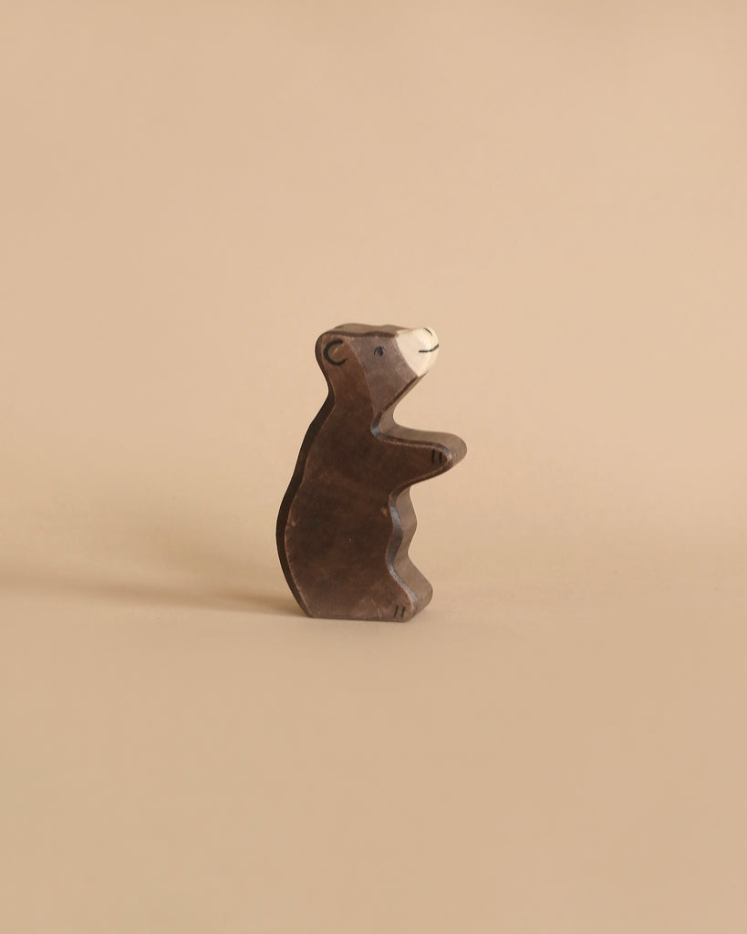 A small brown bear from the Holztiger Handmade Wooden Woodland Animals Set, handcrafted from maple and beech wood, stands upright on a plain beige background.