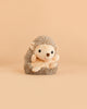 The Bukowski - Sweet Hubert Hedgehog - Sitting features a round face, small black eyes, and a soft tan body; it sits upright against a solid beige background, making it the perfect safe toy companion for nap time.