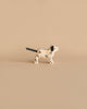 A small, white, Dalmatian-shaped candle with black spots and a black wick for a tail stands on a beige surface, echoing the charming style of the Holztiger Handmade Wooden Farm Animals Set.