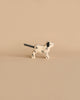 A small, minimalist wooden dog figurine painted white with black spots stands against a beige background. Handcrafted in Europe, this Holztiger Dalmatian Dog, Small figure's tail is black and slightly elevated. The scene is simple and uncluttered, focusing solely on the artisanal dog figurine.