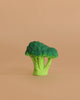 Brucy the Broccoli Teething Toy, a green plastic broccoli floret, sits on a plain light brown background—perfect for teething or sensory play.