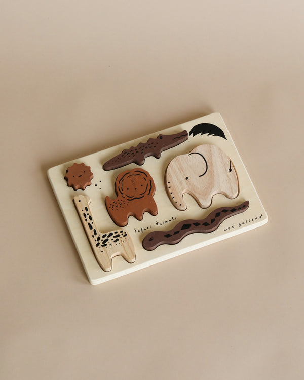A Wooden Tray Puzzle - Safari Animals on a beige surface featuring various animal shapes like a whale, elephant, and others, each piece labeled with its name.
