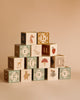 A pyramid of the Newborn Gift Set - Pink blocks, each featuring a letter and illustrations like animals, a mushroom, flower, and strawberry, arranged against a plain beige background.