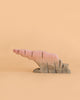 A Bumbu Handmade Wooden Howl Stone, painted in pink and brown hues, mimics an abstract, jagged rock formation against a plain beige background—inviting imaginative play and capturing the whimsical spirit of a Howlstone toy.