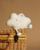 The Mon Ami - Soft Cloud Plush Toy, featuring closed eyes, a blue star, and striped legs, sits on a wicker basket against a brown background—an irresistibly cozy accent for any room.