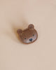 A cute Donsje Leather Hair Tie - Bear face patch with stitched details on a beige background. The bear has small, round ears and a black nose and mouth.