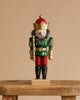 The Christian Ulbricht Collectible Wooden Nutcracker – King (Red and Green) features a gold crown, gray hair, and a red and green uniform, standing on a small wooden bench against a plain beige background.