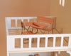 Bring your Maileg dollhouse to life with the Maileg Fully Furnished Dollhouse Set + Gift With Purchase (Restock Expected In August), featuring a delightful miniature patio scene complete with elegant dollhouse furniture—including a small wooden table, two chairs, a bench, and a single carrot placed atop the table inside a charming white balcony model—perfect for enhancing any miniature dollhouse setting.