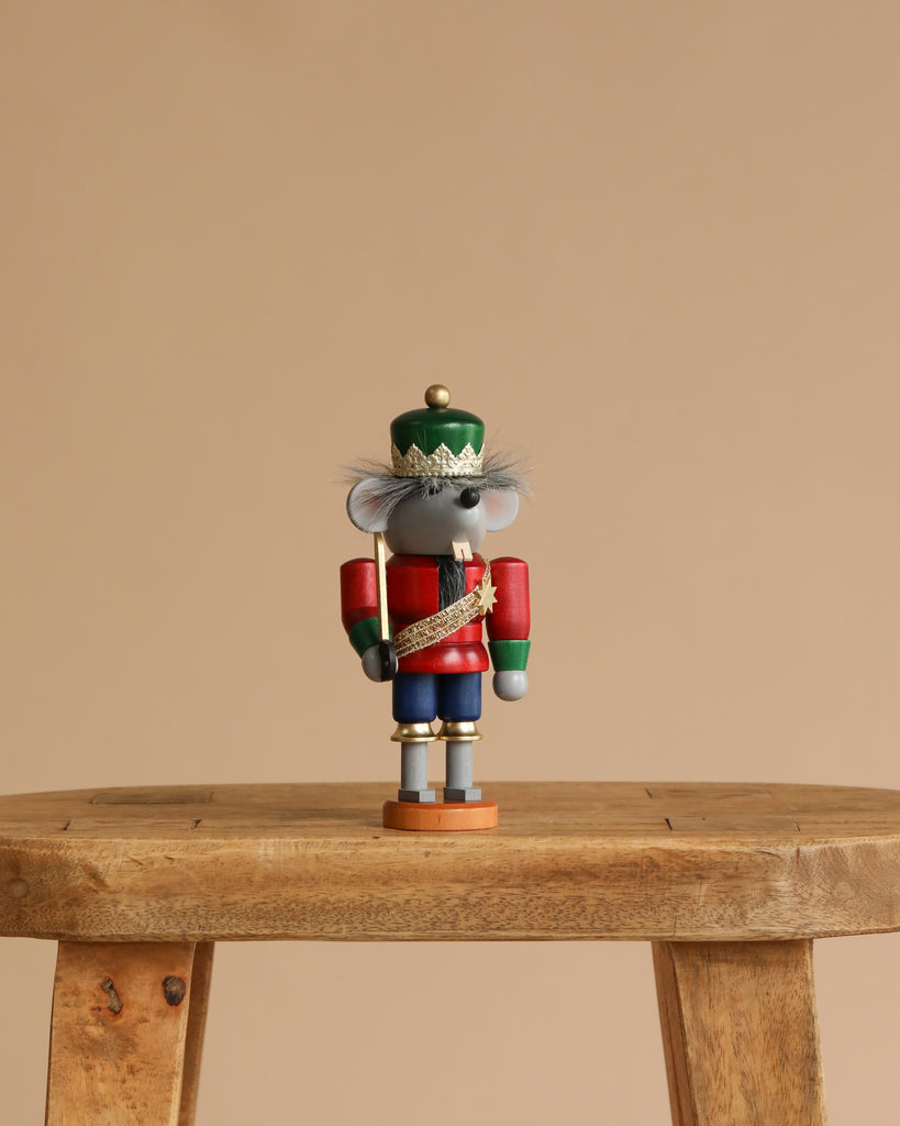 A Christian Ulbricht Collectible Wooden Nutcracker - Mouse King stands on a wooden stool against a plain beige background.