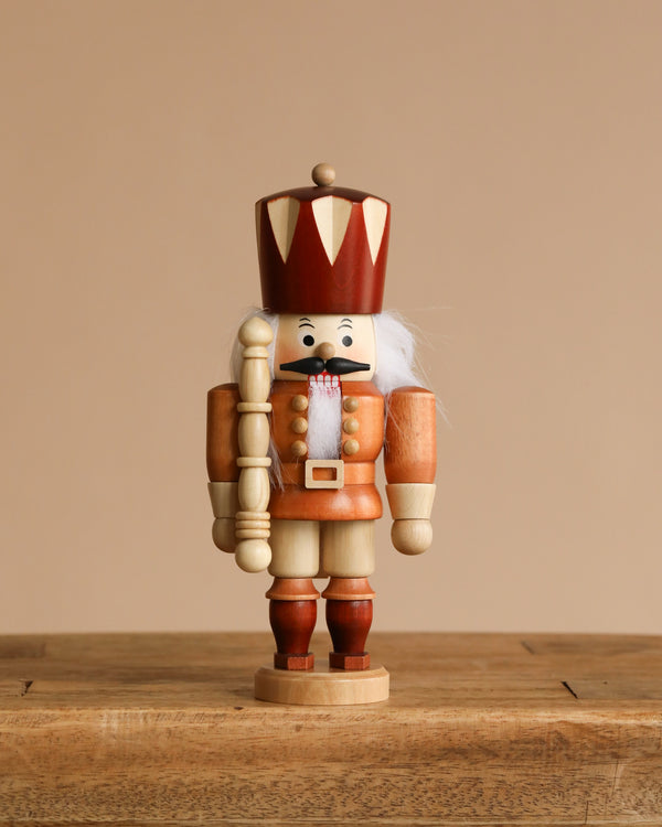 The Christian Ulbricht Collectible Wooden Nutcracker - King (Natural) stands on a rustic wooden surface against a plain beige background.