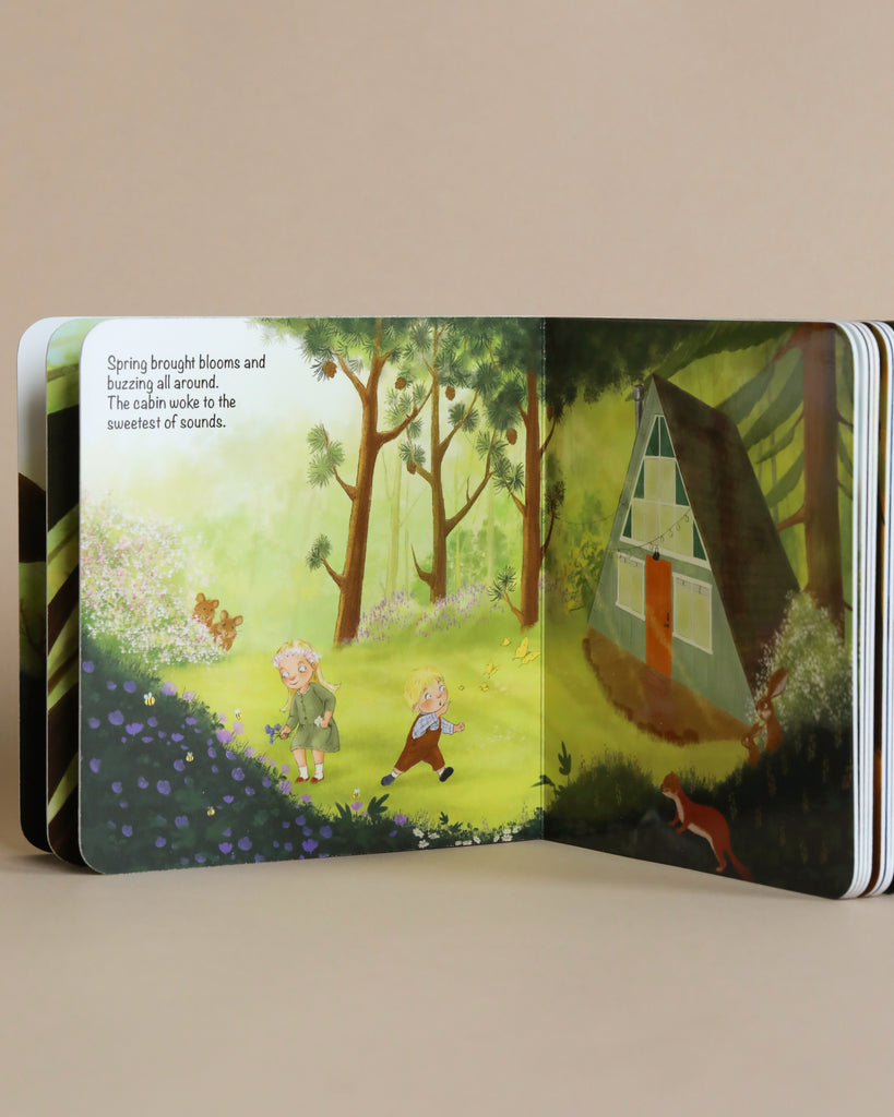 Open The Happy A-Frame In The Woods Book showing an illustration of two kids walking in a lush forest with blooming flowers and birds. The text describes spring awakening nature with blooms and sounds.
