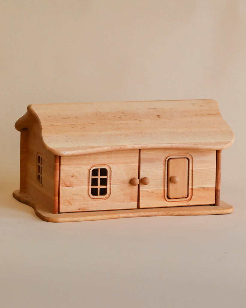 A handcrafted wooden model of a Handmade Wooden Dollhouse Cottage with detailed windows, a door, and a smooth, polished finish, set against a plain light-colored background.