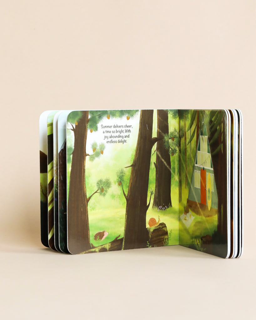 The Happy A-Frame In The Woods Book is open, showing a vibrant, illustrated forest scene with animals and a poem about summer on the pages. The book stands on edge, fanning out with multiple pages visible.