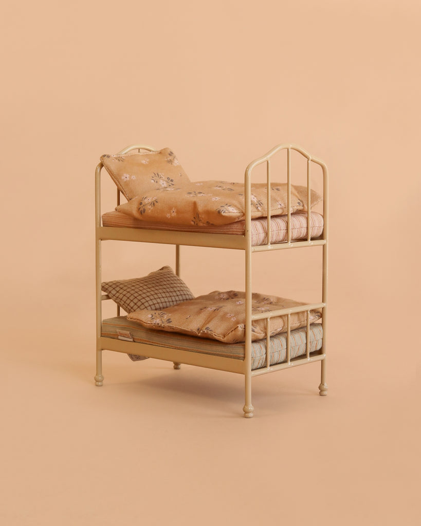 The Maileg Bunk Bed Bedroom Set features a small, cream-colored bunk bed complete with floral bedding and pillows, set against a plain beige background—making it an ideal and charming addition to your dollhouse accessories.