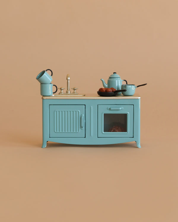 The Maileg Blue Kitchen Set—a small, vintage-style kitchen with sink, faucet, cabinets, teapot, cups, bowl, and bread—perfect for any Mouse—displayed against a plain beige background.