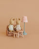 Two stuffed bunny dolls sit on the Maileg Little Rabbit’s Living Room Set, which includes a polka-dot sofa bed, blue floor lamp, wooden table, and stool, all arranged against a plain beige background.