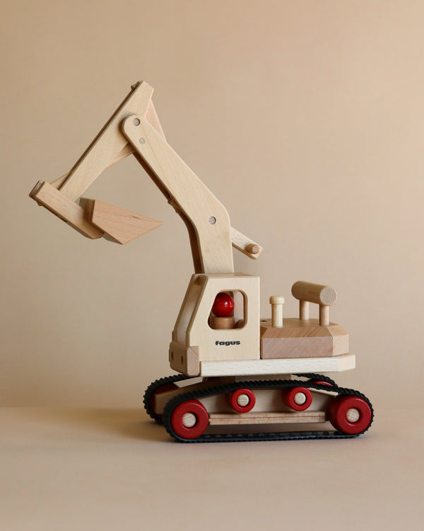 A Fagus Wooden Excavator toy with movable parts positioned against a plain beige background. The model includes red-wheeled tracks and small wooden levers.