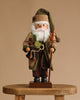 The Christian Ulbricht Collectible Wooden Nutcracker - Forest Santa Limited Edition 2500 holds a staff and a gift sack, standing on a wooden stool against a plain beige background.