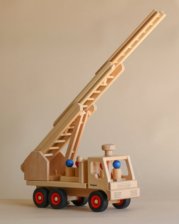 A Fagus Wooden Fire Truck featuring a detailed ladder extended upwards, red wheels, and two firefighter peg figures in the driver's cabin, set against a neutral background.