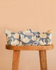 The Konges Sloejd Doll Lift - Swan, crafted from OEKO-TEX certified cotton and adorned with a blue and white swan pattern, sits atop a wooden stool against a peach background. Offering both style and practicality for playtime, this charming basket ensures safety and comfort for your little one’s favorite toys.