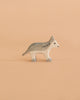 The Holztiger Wolf, Small is a minimalist wooden figurine depicting a gray and white wolf, set against a solid light peach background. Expertly handcrafted in Europe, this charming piece is part of the renowned HOLZTIGER figures collection and reflects a tradition of meticulous craftsmanship.