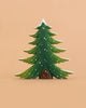 The Bumbu Handmade Wooden Snowy Fir Tree, Large, is a Montessori-inspired, eco-friendly wooden toy featuring stylized green branches accented with white snow, showcased against a plain peach background.